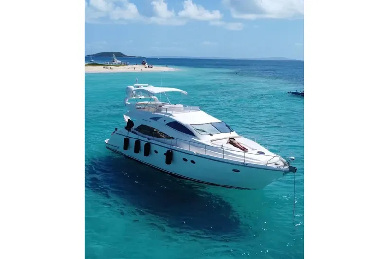  Yacht Photos Pics Luxury Aicon 56 yacht from 2007 on turquoise waters near a sandy beach.