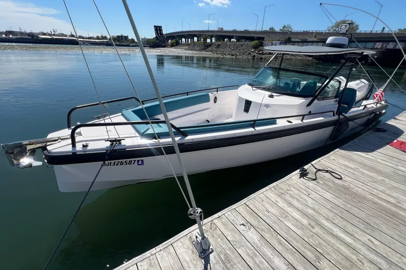  Yacht Photos Pics 2021 Axopar 28 boat docked on calm water near a bridge.