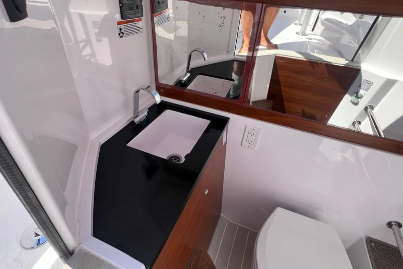  Yacht Photos Pics 2021 Axopar 28 boat interior bathroom with sink, mirror, and toilet.