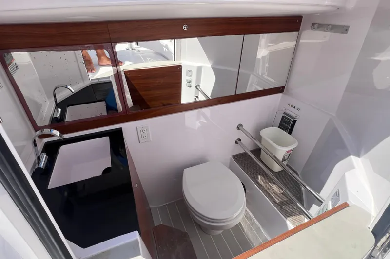  Yacht Photos Pics 2021 Axopar 28 boat bathroom with modern fixtures and wood accents.
