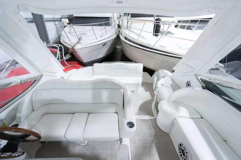 This Is Dope Yacht Photos Pics 2005 Formula 40 Cruiser interior with white seating and helm, docked alongside other boats.