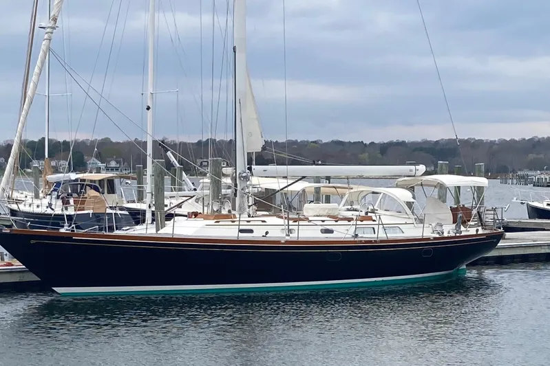 Symphony V Yacht Photos Pics Hinckley Sou'wester 52 sailboat from 1999 docked in a marina, under a cloudy sky.