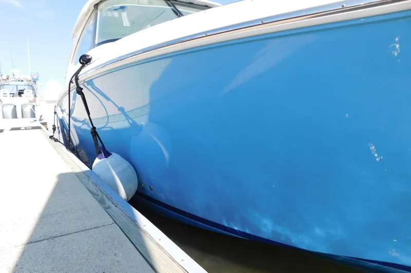  Yacht Photos Pics 2024 Pursuit DC 326 Dual Console boat docked with blue hull and fender.