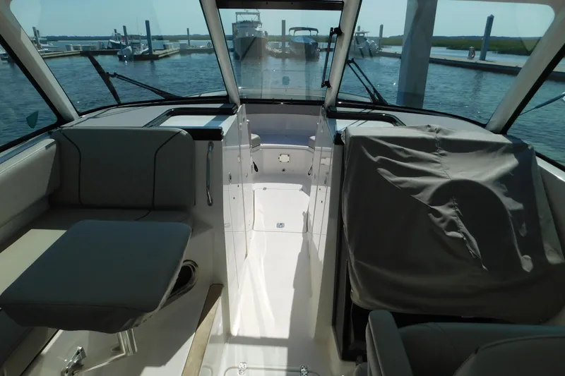  Yacht Photos Pics 2024 Pursuit DC 326 Dual Console interior with seating and covered helm, docked at marina.