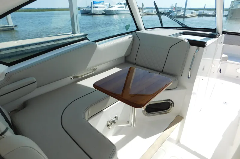  Yacht Photos Pics 2024 Pursuit DC 326 Dual Console interior with elegant seating and wooden table.