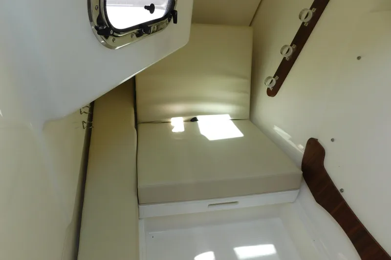  Yacht Photos Pics 2024 Pursuit DC 326 Dual Console cabin interior with cushioned seating and porthole window.