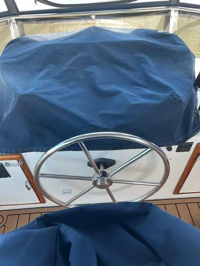 Ronda-vous Yacht Photos Pics Steering wheel of a 1990 Jefferson 42 Viscount Sundeck boat, covered in blue fabric.