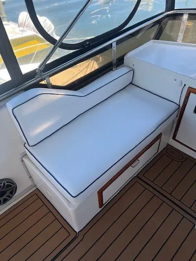 Ronda-vous Yacht Photos Pics 1990 Jefferson 42 Viscount Sundeck interior with white cushioned seating and wood accents.