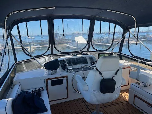 Ronda-vous Yacht Photos Pics Interior view of 1990 Jefferson 42 Viscount Sundeck yacht with helm and marina background.