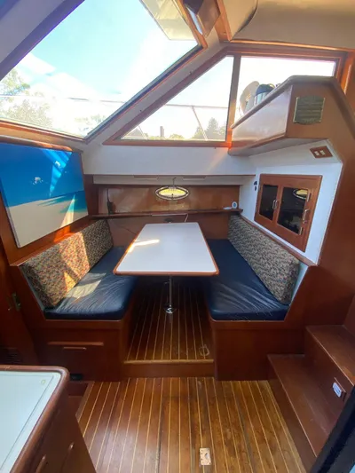 Ronda-vous Yacht Photos Pics 1990 Jefferson 42 Viscount Sundeck interior with dining area, wooden flooring, and skylight.