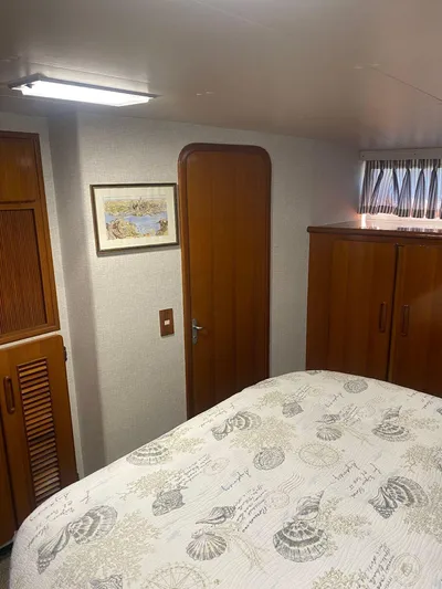 Ronda-vous Yacht Photos Pics 1990 Jefferson 42 Viscount Sundeck bedroom with wooden cabinets and nautical-themed bedding.