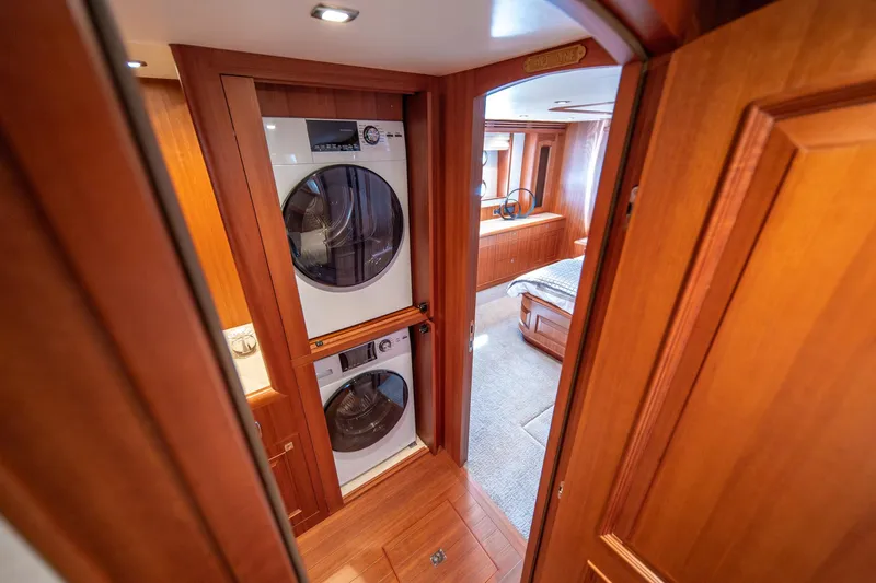750 Skylounge Yacht Photos Pics Laundry area inside 2022 Hampton Endurance 750 LRC yacht, featuring stacked washer and dryer.