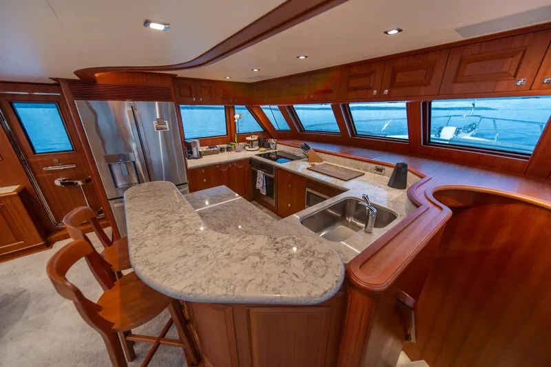 750 Skylounge Yacht Photos Pics Luxurious kitchen interior of 2022 Hampton Endurance 750 LRC yacht with wooden cabinetry and marble countertops.