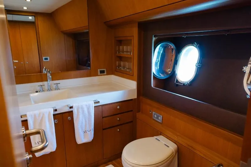 Mare Blu Yacht Photos Pics Luxurious bathroom in 2008 Pro Boat Yachts Power Cat 80, featuring wood cabinetry and porthole window.