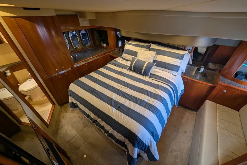  Yacht Photos Pics Luxurious 2007 Cruisers Yachts 520 Express cabin with striped bedding and elegant wood finishes.