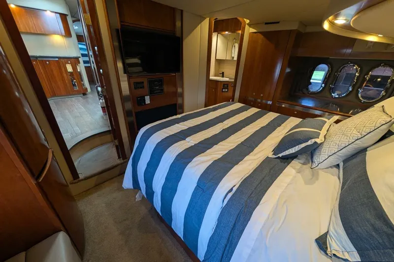  Yacht Photos Pics Luxurious 2007 Cruisers Yachts 520 Express bedroom with striped bedding and elegant wood finishes.