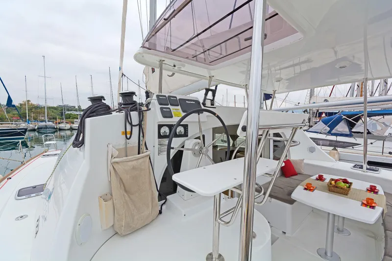 Cataki Yacht Photos Pics 2017 Lagoon 380 S2 yacht cockpit with steering wheel and dining area in marina.