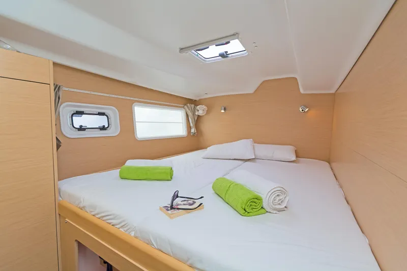 Cataki Yacht Photos Pics Cozy cabin interior of 2017 Lagoon 380 S2 with neatly arranged bed and porthole windows.