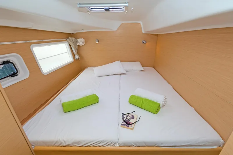 Cataki Yacht Photos Pics Cozy cabin interior of 2017 Lagoon 380 S2 catamaran with bed, towels, and reading materials.