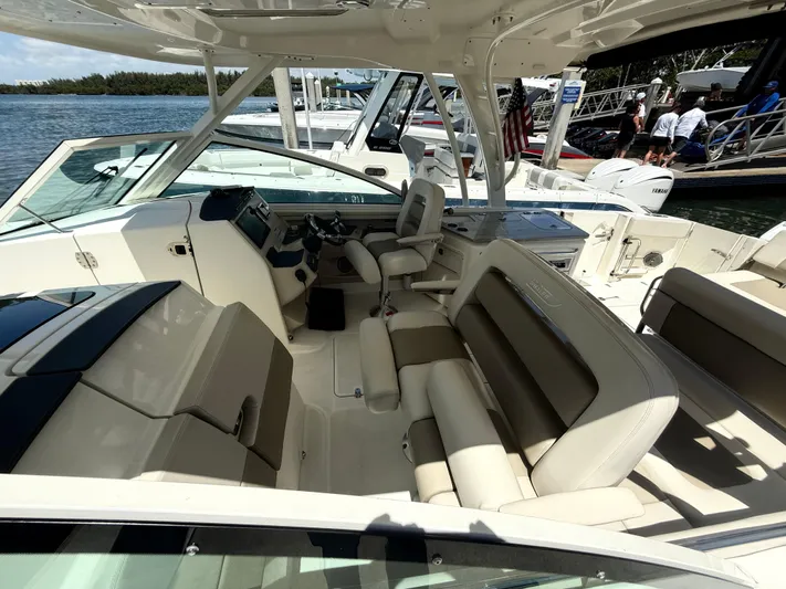  Yacht Photos Pics 2017 Boston Whaler 320 Vantage boat interior with seating and helm, docked by the water.