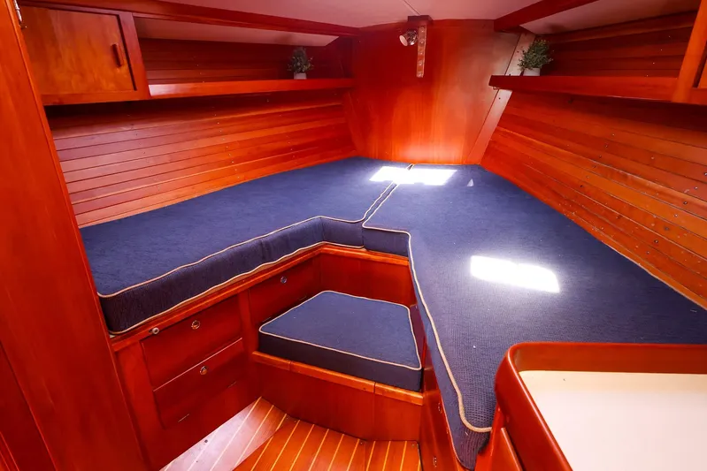 Hamburg II Yacht Photos Pics Cozy cabin interior of 2002 J Boats J/46 with wooden finish and blue cushions.