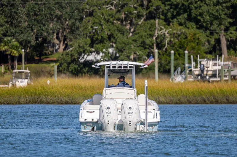  Yacht Photos Pics 2024 Sea Hunt Escape 28 boat cruising on a scenic waterway with lush greenery.