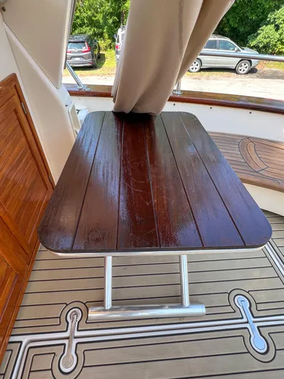 A'maure Yacht Photos Pics Wooden table on 2001 Apreamare 11 yacht deck, with curtain and parked cars visible.