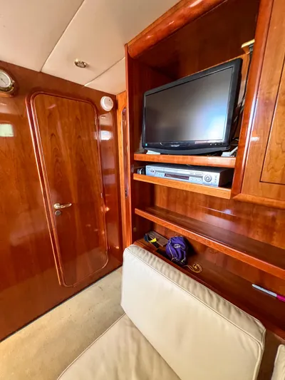 A'maure Yacht Photos Pics Interior of 2001 Apreamare 11 yacht with TV, wooden cabinetry, and beige seating.
