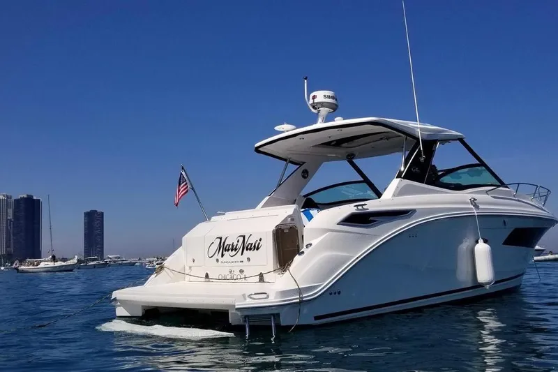  Yacht Photos Pics 2019 Sea Ray Sundancer 320 yacht on water, city skyline in background.