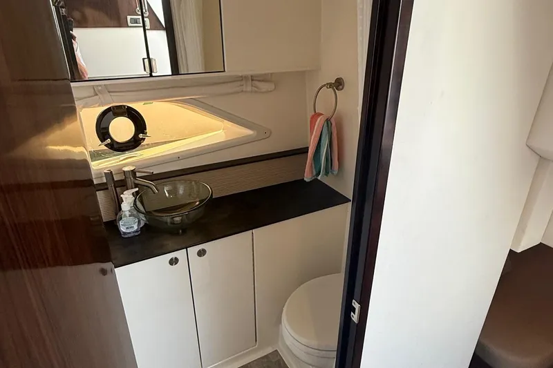  Yacht Photos Pics 2019 Sea Ray Sundancer 320 bathroom with modern sink, mirror, and porthole window.