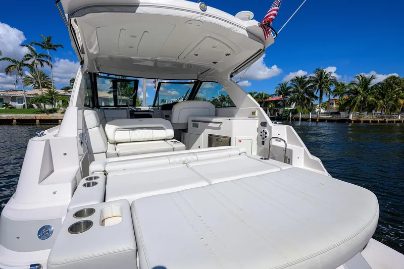 Damn Daddy Yacht Photos Pics 2020 Regal 35 Sport Coupe yacht with luxurious seating, docked by palm trees and waterfront homes.