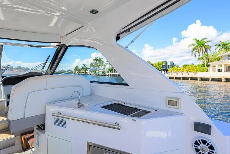 Damn Daddy Yacht Photos Pics 2020 Regal 35 Sport Coupe interior with kitchenette, overlooking scenic waterfront and palm trees.