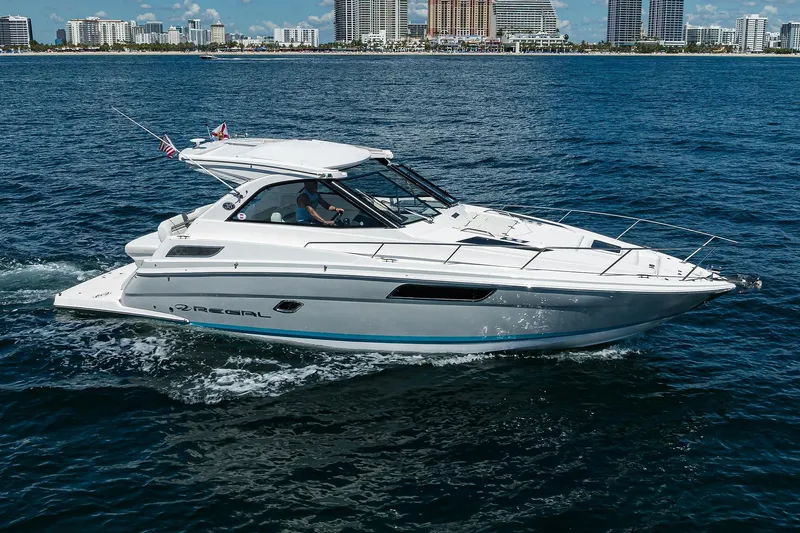 Damn Daddy Yacht Photos Pics 2020 Regal 35 Sport Coupe cruising on ocean with city skyline backdrop.
