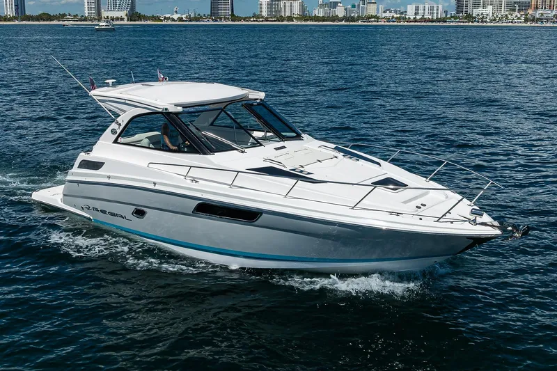 Damn Daddy Yacht Photos Pics 2020 Regal 35 Sport Coupe cruising on open water with city skyline in background.