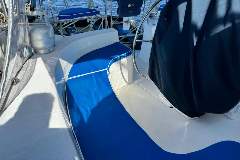 Orion Yacht Photos Pics 2002 Hunter 410 sailboat cockpit with blue cushions and steering wheel, docked on water.