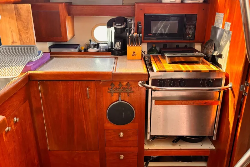 Orion Yacht Photos Pics Compact kitchen in a 2002 Hunter 410 yacht with wooden cabinetry and modern appliances.