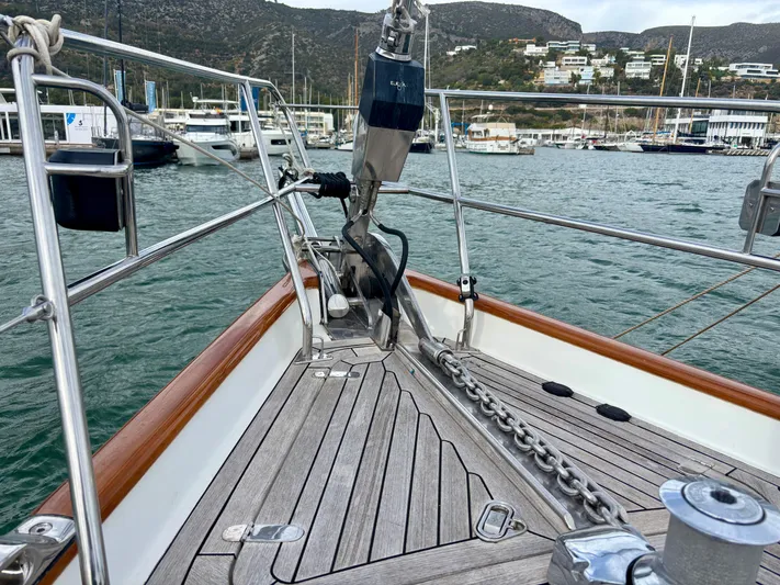  Yacht Photos Pics Deck view of 2003 Oyster 56 yacht in marina, showcasing anchor chain and scenic background.