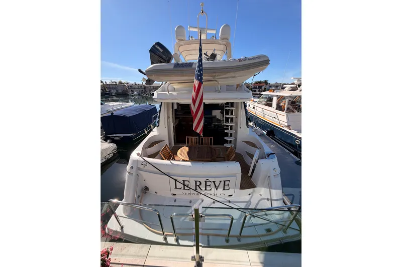 Le Reve Yacht Photos Pics 1999 Carver 530 Voyager Pilothouse yacht docked, featuring an American flag and upper deck dinghy.