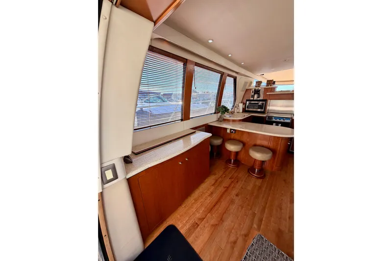 Le Reve Yacht Photos Pics Interior of 1999 Carver 530 Voyager Pilothouse with wooden cabinetry and bar stools.