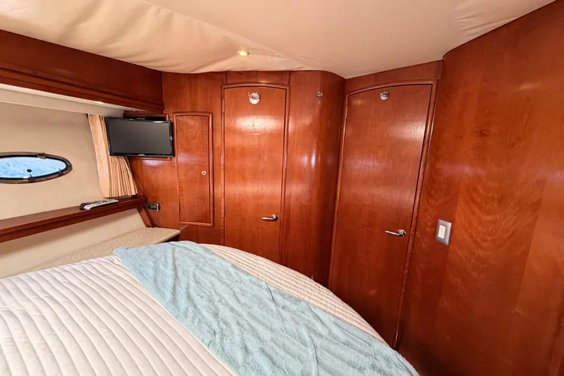 Le Reve Yacht Photos Pics Luxurious 1999 Carver 530 Voyager Pilothouse bedroom with wood paneling and porthole window.