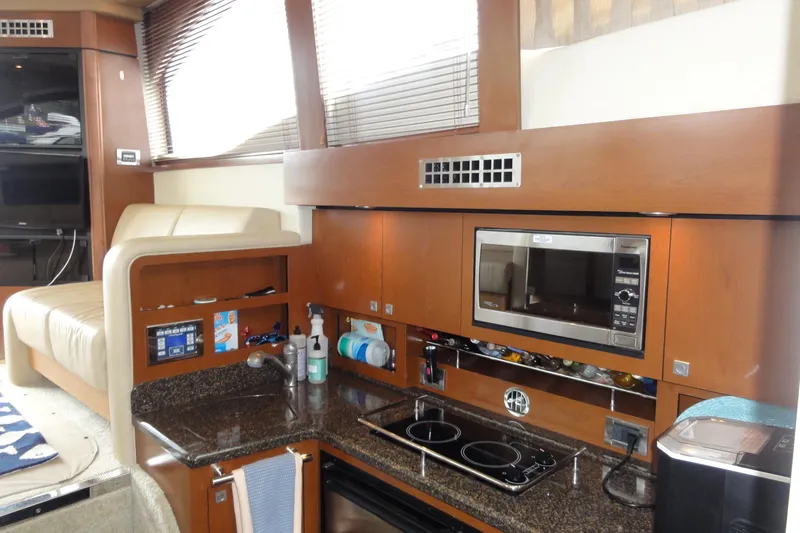  Yacht Photos Pics 2007 Sea Ray 36 Sedan Bridge interior kitchen with microwave, stove, and wooden cabinetry.
