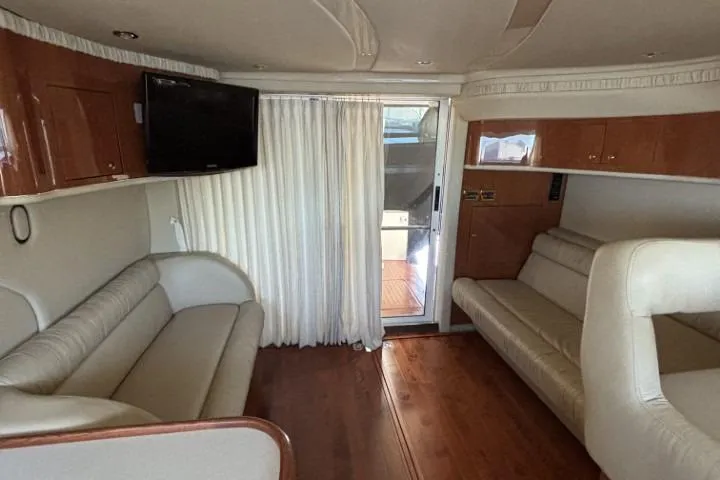 Gazoo Yacht Photos Pics Interior of 2001 Sea Ray 400 Sedan Bridge with sofas, TV, and wooden flooring.