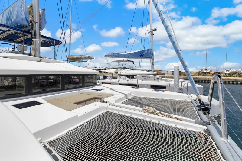 Happy Ours Yacht Photos Pics 2022 Lagoon 52 F catamaran docked, featuring spacious deck and netting under blue sky.
