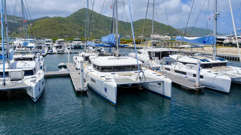 Happy Ours Yacht Photos Pics 2022 Lagoon 52 F catamarans docked at a marina with scenic mountain backdrop.