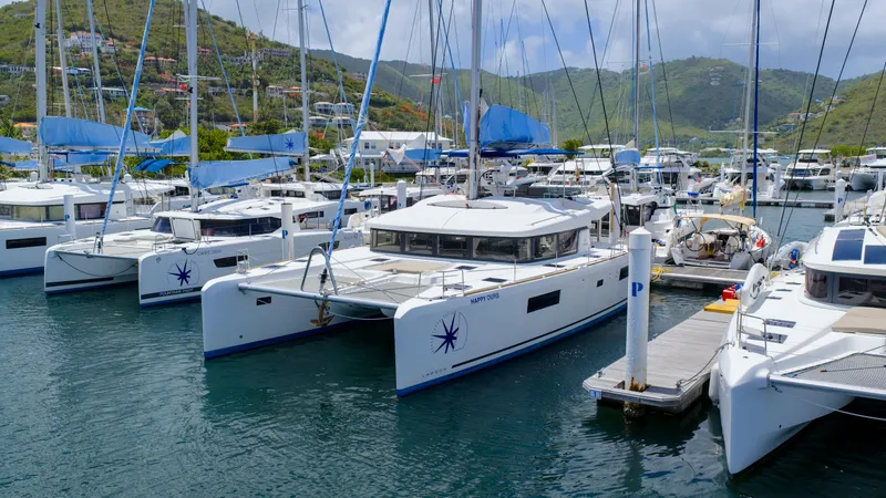 Happy Ours Yacht Photos Pics 2022 Lagoon 52 F catamarans docked in a scenic marina with lush hills in the background.