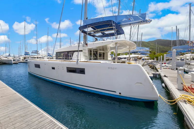 Happy Ours Yacht Photos Pics 2022 Lagoon 52 F catamaran docked in a marina under a clear blue sky.