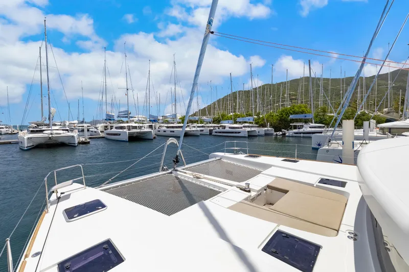Happy Ours Yacht Photos Pics Lagoon 52 F catamaran docked in marina, surrounded by sailboats, under a clear blue sky.