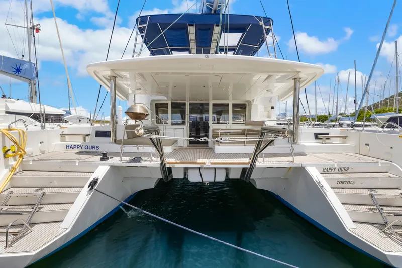 Happy Ours Yacht Photos Pics 2022 Lagoon 52 F catamaran docked, rear view, with blue sky and marina background.