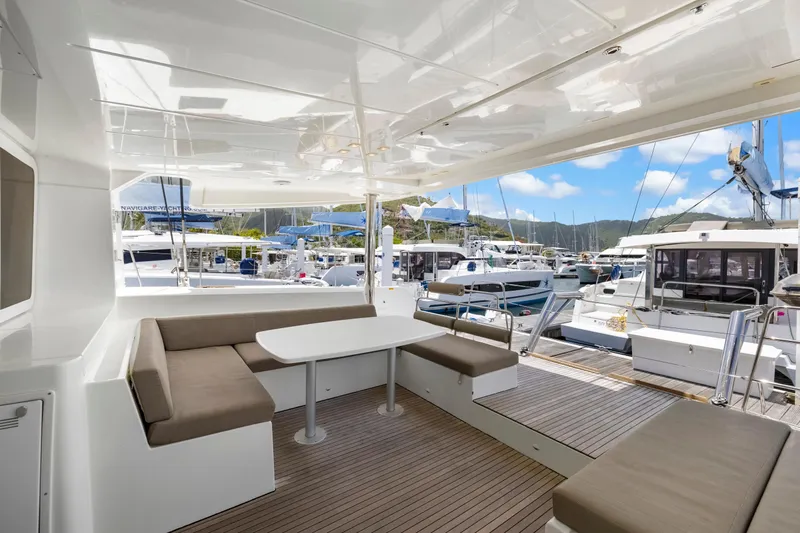 Happy Ours Yacht Photos Pics Spacious deck of 2022 Lagoon 52 F yacht with seating area in marina.