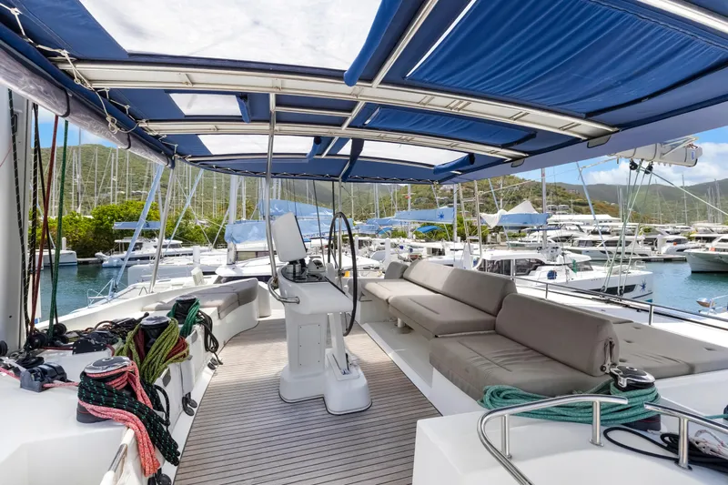 Happy Ours Yacht Photos Pics Luxurious 2022 Lagoon 52 F catamaran with spacious deck and seating in a marina.